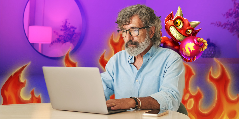 Señor de 50 años sentado en una mesa jugando en su computadora.