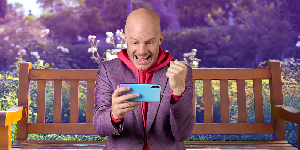 Facundo sentado en una banca del parque, entretenido jugando en su smartphone